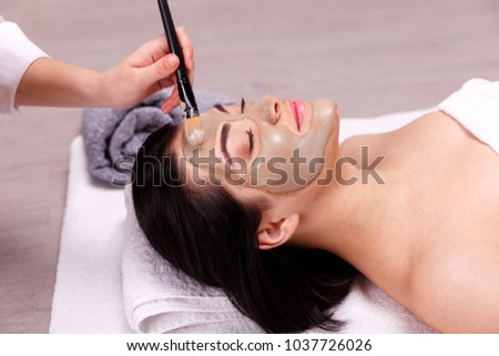 Spa facial mask application. Beautiful relaxed woman having clay face mask in the spa Royalty-Free Stock Photo #1037726026