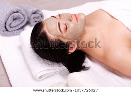 Spa facial mask application. Beautiful relaxed woman having clay face mask in the spa Royalty-Free Stock Photo #1037726029
