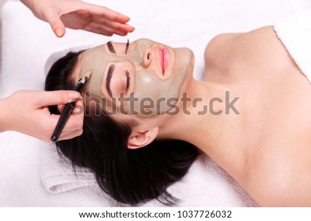 Spa facial mask application. Beautiful relaxed woman having clay face mask in the spa Royalty-Free Stock Photo #1037726032