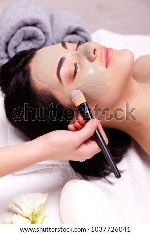Spa facial mask application. Beautiful relaxed woman having clay face mask in the spa Royalty-Free Stock Photo #1037726041