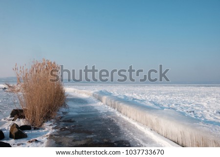 icicles and ice at frozen lake Balaton, hills in background.
