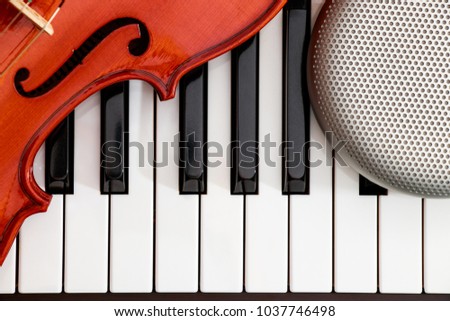 violin and speaker closeup on to the piano keyboard background