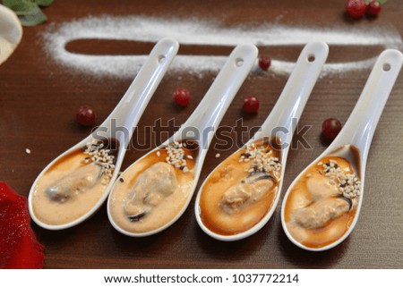 party appetizers. Four white spoons with mussels Spanish Tapas . Extreme close up macro picture. Fresh juicy mussels with red pepper on a white porcelain spoon. Seafood dish. Food photography. Fresh