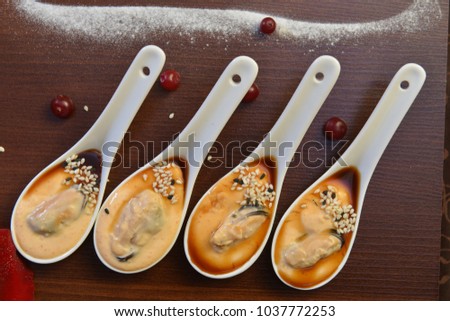 party appetizers. Four white spoons with mussels Spanish Tapas . Extreme close up macro picture. Fresh juicy mussels with red pepper on a white porcelain spoon. Seafood dish. Food photography. Fresh