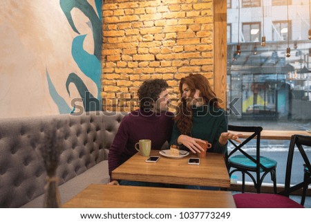 Cheerful young man and woman are talking in cafe. They are sitting at table and drinking coffee. Romantic date concept