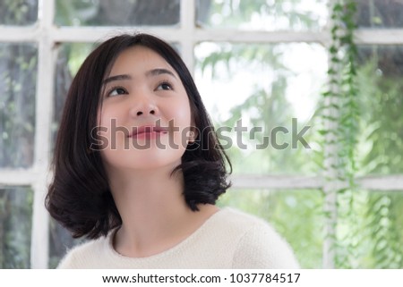 Beautiful asian teenage  in green garden is looking something at upper side