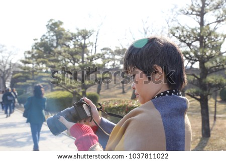 The Asian woman holding mirrorless camera.
