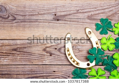 Golden horseshoe and clover leaves on old wooden boards. St.Patrick's day holiday symbol. Space for text.