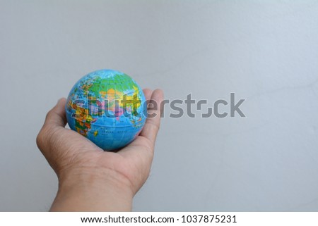 Hand holding model globe on white background.