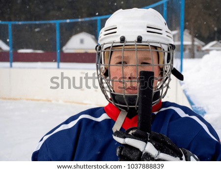 The boy plays hockey on a street skating rink.A boy on the street playing hockey.