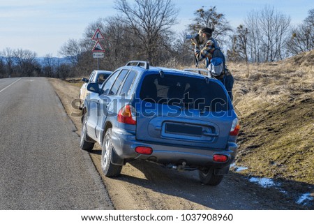The young man is shooting from the car