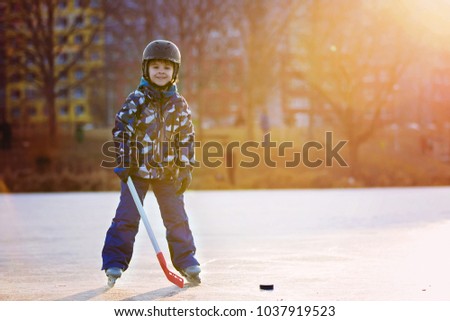 Children, boys, friends and brothers playing hockey and skating in the park on frozen lake, wintertime on sunset