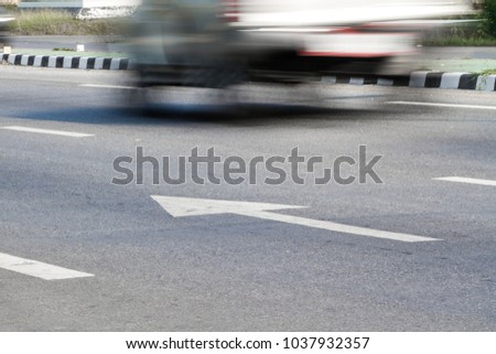 White arrow pointing to the front on the road surface with running cars.