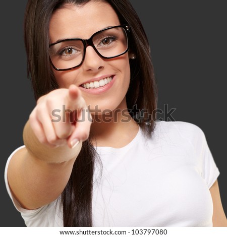 portrait of a young woman pointing with her finger against a black background