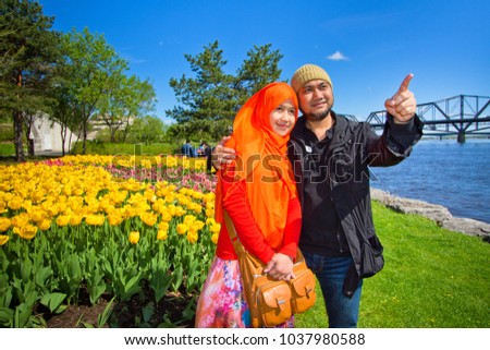 A Muslim couple from Asia taking picture with tulip flowers as background during Ottawa tulip festival