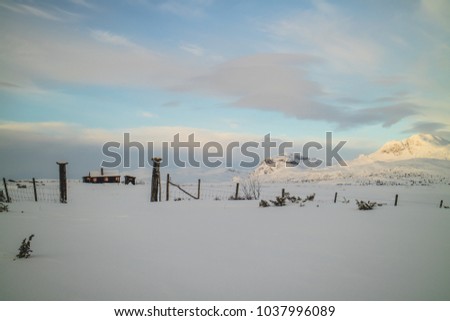 Cozy hut covered with snow in a fantastic winter scenery with majestic mountains in the horizon