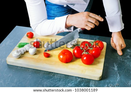 Professional chef cuts vegetables with a sharp knife from Damascus steel. Mixed media