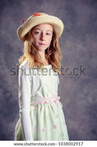 nice girl with blond hair in white dress and straw hat looking in to the camera