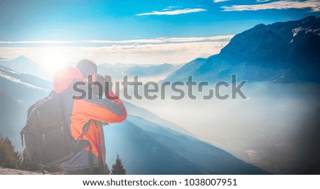 Man photographing the alpine landscape at dawn on the snow in the high mountains.