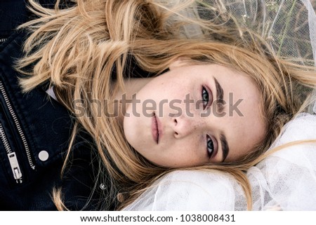 Portrait of a beautiful white blonde girl with freckles on her face that lies on the ground