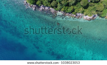 Aerial drone view of beautiful island coastline with rocks and transparent sea water around in sunny summer day