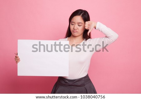 Young Asian woman show thumbs down with white blank sign on pink background