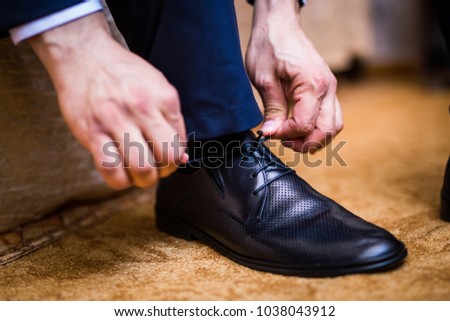 The man wears shoes. Tie the laces on the shoes. Men's style. Professions. To prepare for work, to the meeting Royalty-Free Stock Photo #1038043912