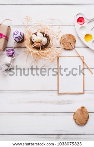 Easter set for coloring eggs concept with paints, brush, blank letter and gifts on a white wooden background