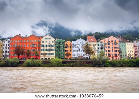 Innsbruck colorful houses along the river. Fog over mountains in rainy day