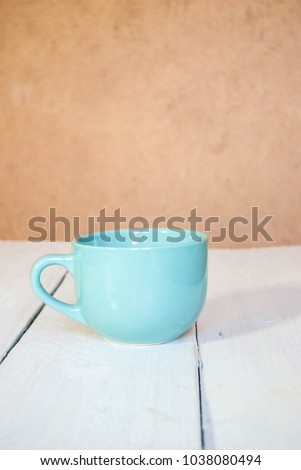 
big blue mug on white wooden table with brown background for mockup. vertical orientation of the frame