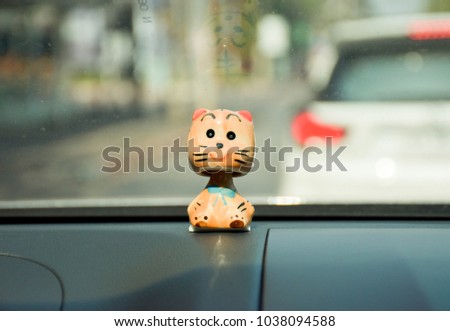 Cat ceramic doll on console of car. Focus cat.