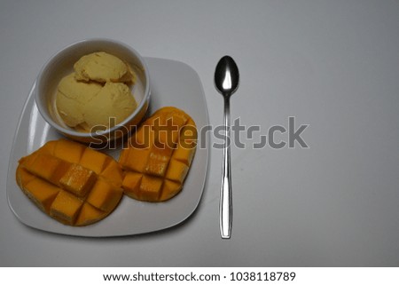 Bowl of homemade mango ice cream and sliced mangoes. 