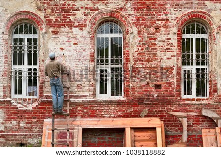 Working restorer restores the old wall of the building. Texture of old brick wall Royalty-Free Stock Photo #1038118882