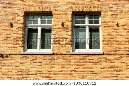 Two white windows against a green wall in the city of Brugge, Belgium, Europe on a bright summer day