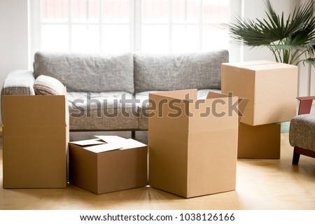 Cardboard carton boxes with personal belongings household stuff in modern living room, many packed containers on moving day in new home, relocation or house removals delivery service concept Royalty-Free Stock Photo #1038126166
