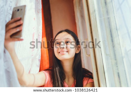 A teenage girl makes selfie on a cell phone.