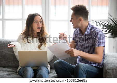 Worried unhappy couple arguing about debt or high domestic bills with laptop and documents, young family having quarrel discussing wasting money bankruptcy problem sitting together on sofa at home Royalty-Free Stock Photo #1038126685
