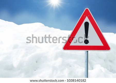 Snowfall on the road with a warning sign