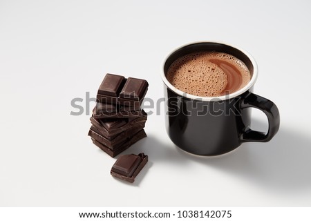 Black mug with hot chocolate served with chunks of dark chocolate 