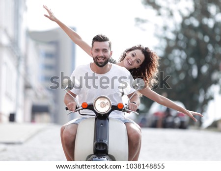 Happy young couple riding a scooter in the city on a sunny day