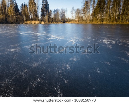 Beautiful Photo of a Frozen Lake in Sunny Autumn Day in an October, with a Sun Shining at Tree line on the coast of Lake