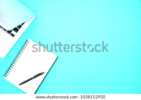 Top view office table desk. Workspace with pen, laptop and notebook page on the pastel indigo blue background.Copy Space for text,Blank word