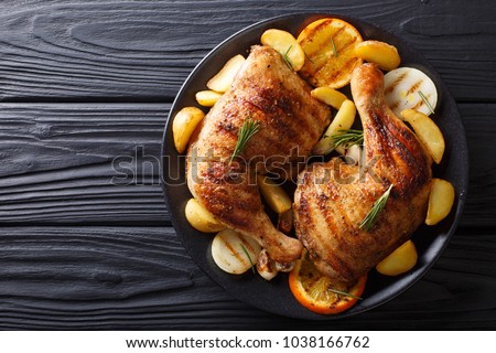 Spicy bbq chicken legs with grilled oranges, onions, garlic and potatoes close-up on a plate on a table. horizontal top view from above
 Royalty-Free Stock Photo #1038166762