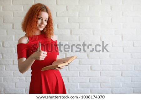 Red-haired girl student on a brick wall background
