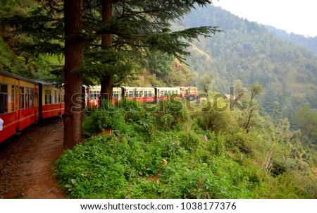 Train moving on mountain slopes, beautiful view, one side mountain, one side valley. Toy train from Shimla to Kalka in India Royalty-Free Stock Photo #1038177376