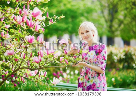 Young beautiful woman under blooming magnolia tree on a spring day