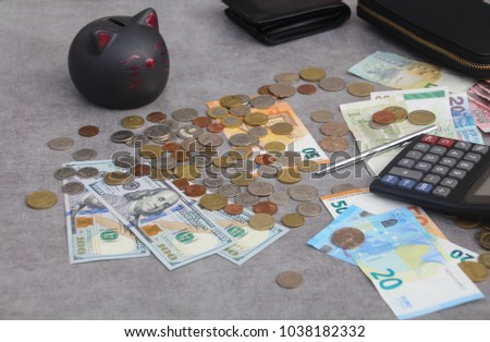 Euro, US Dollar, Hong Kong banknotes and multi currency coins from around the world, a calculator, a pen, wallets  and a cat piggy bank. The concet savings, investments & earnings in a global economy.
