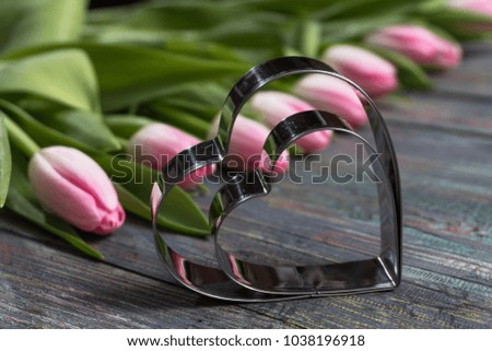 Pink tulips flowers with a metallic heart image on wooden background. Selective focus, place for text