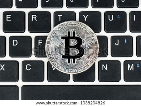 Silver coin bitcoin on laptop keyboard top view