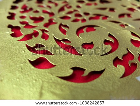 Gold stencil paper block of Thai traditional style art on red fabric.